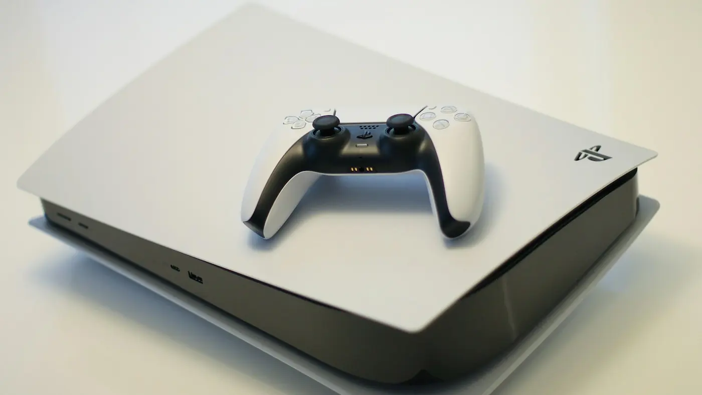 A white PlayStation 5 console with a DualSense controller